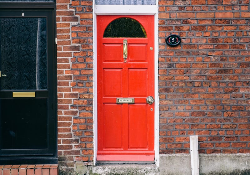 A brick exterior with a red door. 