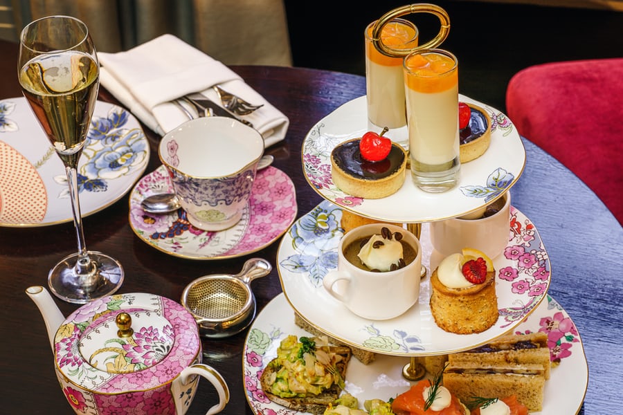 An image featuring tea, flowery pots and plates, and pastries for a London tea. 